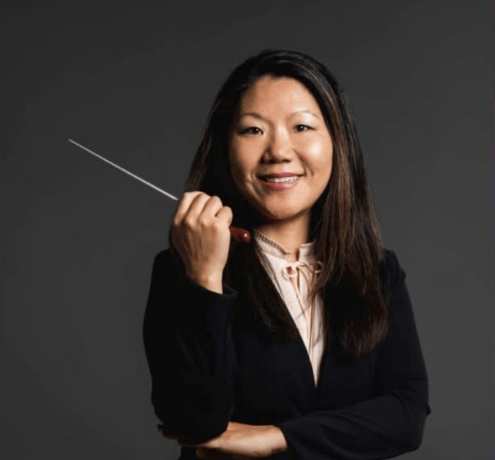 Headshot of a woman with a musical conductor's baton